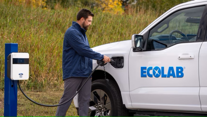 A man plugs a charger into an Ecolab electric vehicle